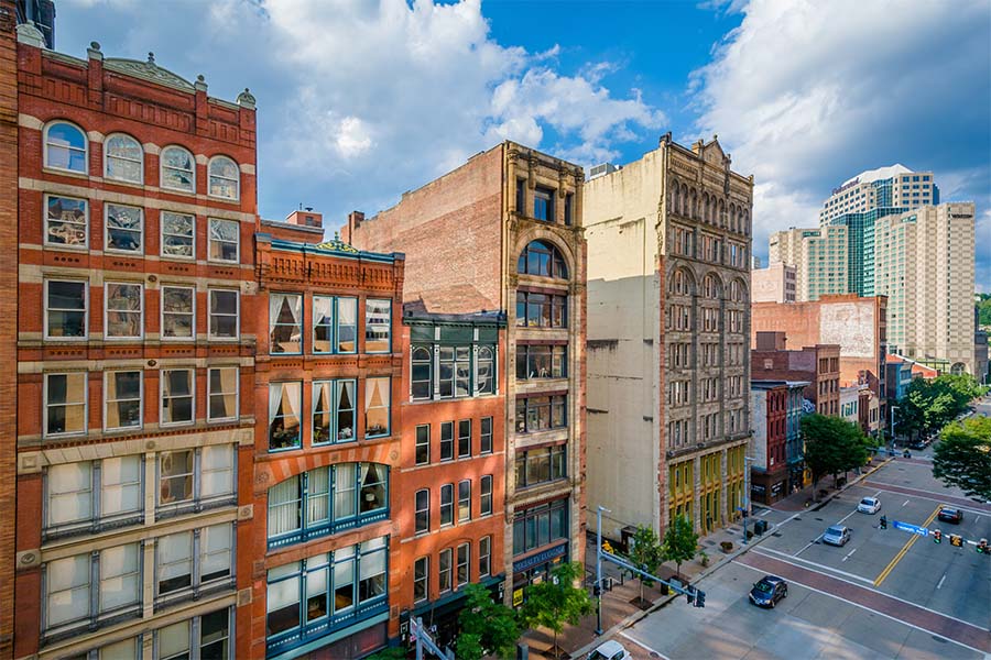 Contact - Row of Colorful Commercial Buildings in Downtown Pittsburgh Pennsylvania Against a Cloudy Blue Sky