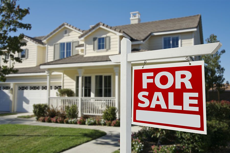 Real Estate - View of a Beautiful Two Story Colonial House with a Green Front Lawn and Landscaping with a For Sale Sign in the Front Yard