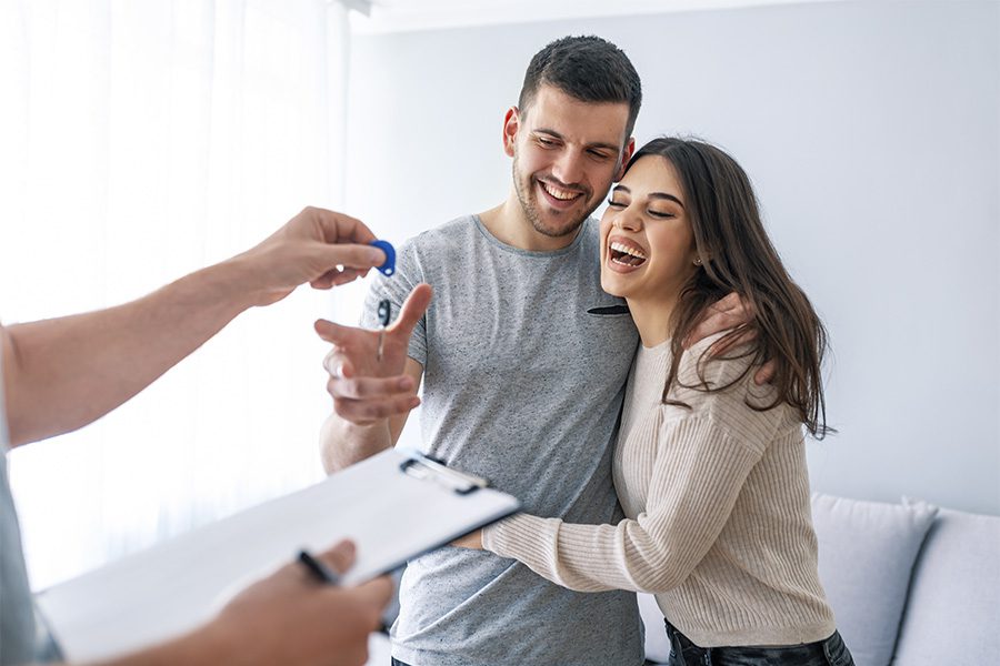 Personal Insurance - Portrait of an Excited Young Couple Getting the Keys to Their New Home from the Realtor