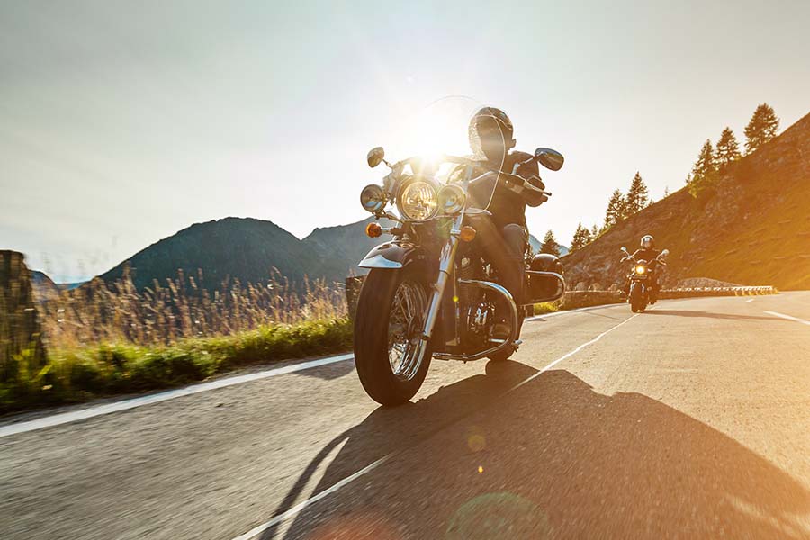 Toys Insurance - View of Two Men Riding Their Motorcylces on a Scenic Road Surrounded by Mountains at Sunset